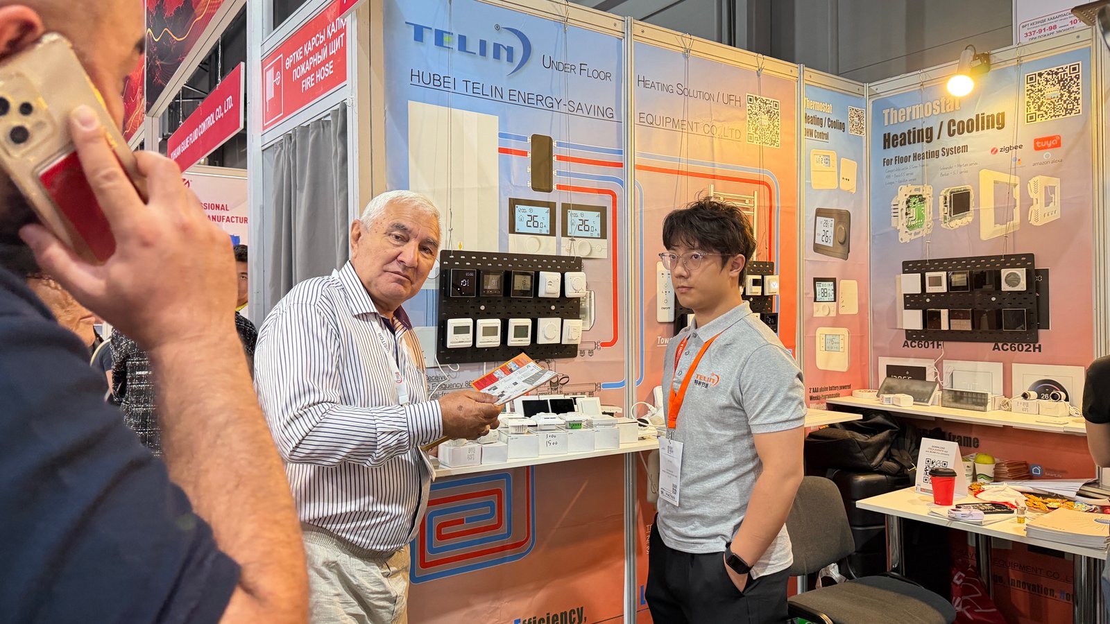 Hubei Telin staff discussing HVAC thermostat with buyers at Kazbuild 2026